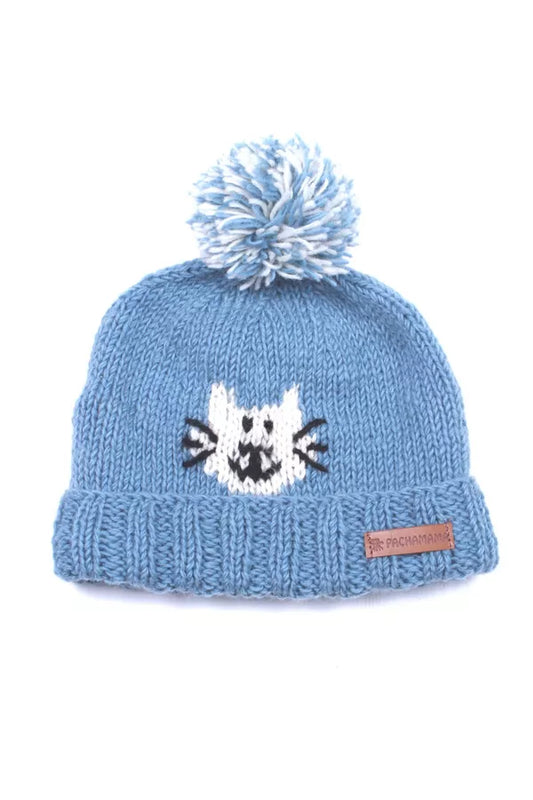 A light blue knit beanie hat with a fluffy pom-pom on top and a white cat face knitted into the front. A small brown brand tag is visible on the cuff.