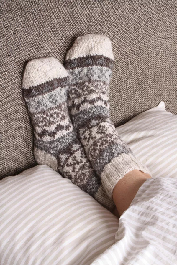 Pair of patterned socks on a person's feet, lying on a textured surface.