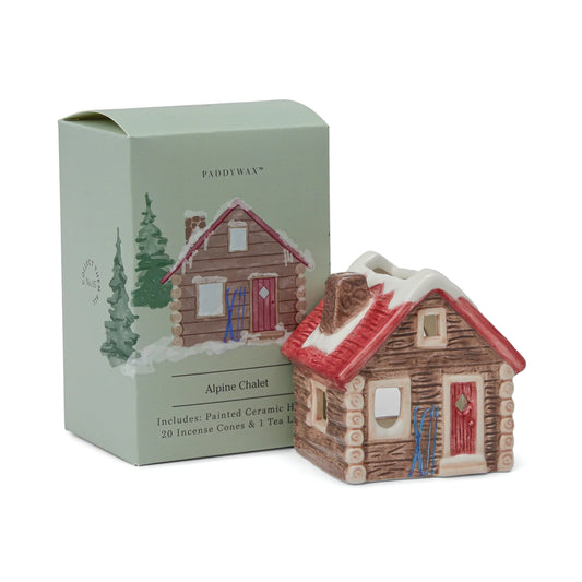 Ceramic Alpine Chalet with snow on the roof next to its packaging on a white background