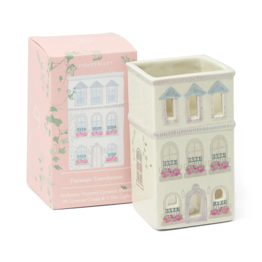 Decorative candle holder with townhouse design next to its packaging on a white background