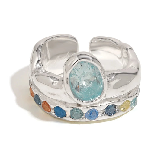 Silver ring with a central blue gemstone and colorful beads on a white background