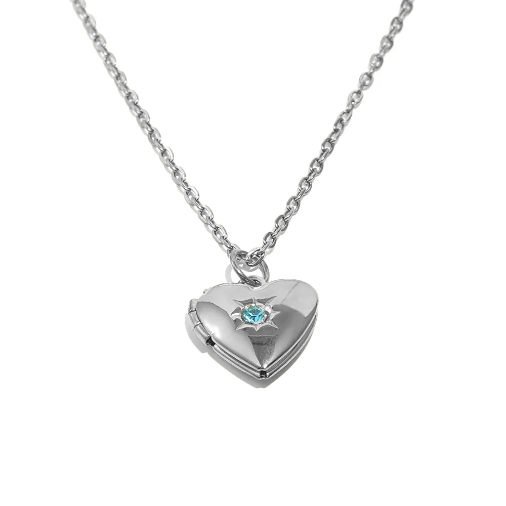 Silver heart-shaped locket with a blue gemstone on a white background