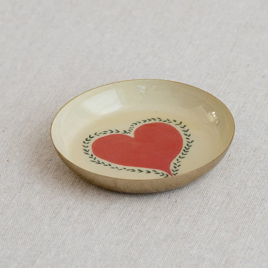 Small ceramic dish with a red heart design on a beige background