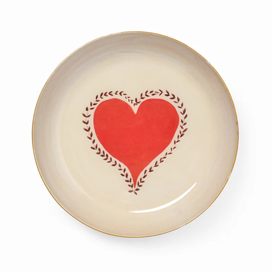 Beige plate with a red heart and green leaves design on a white background