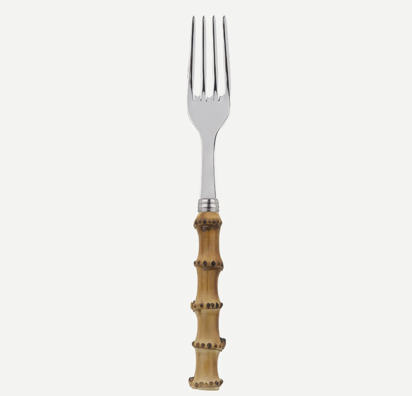 A silver metal serving fork with a decorative natural bamboo handle featuring dark metal rivets, shown against a plain off-white background.