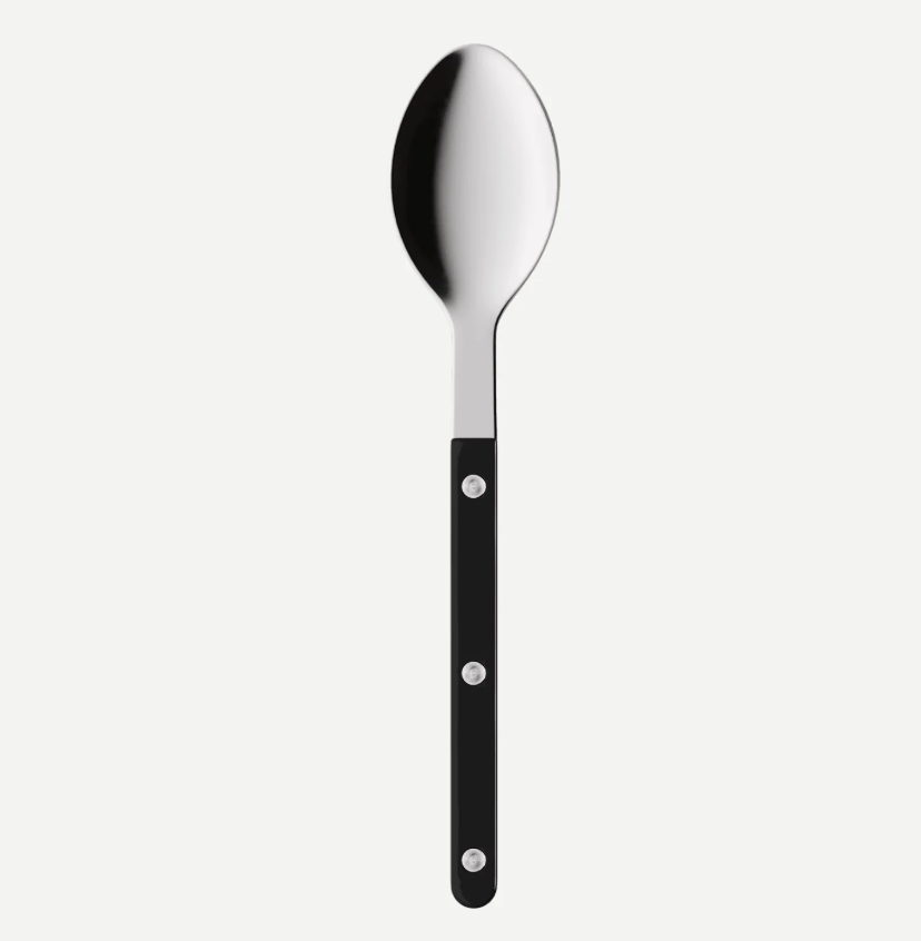 A modern kitchen spoon with a polished silver metal bowl and a sleek black handle secured by three silver rivets, shown against a light gray background.