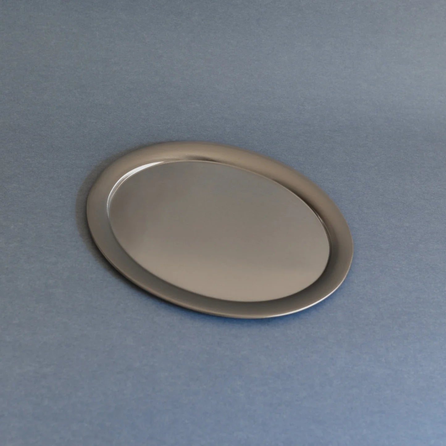 Oval silver tray on a gray background