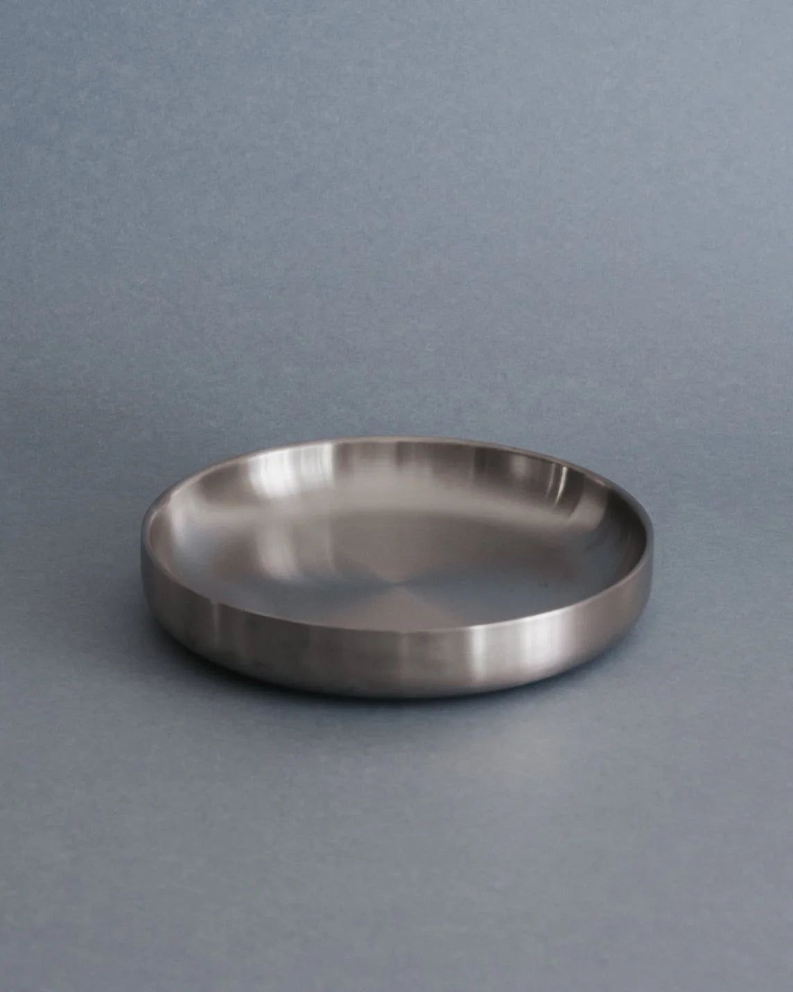 Silver round dinner plate on a gray background