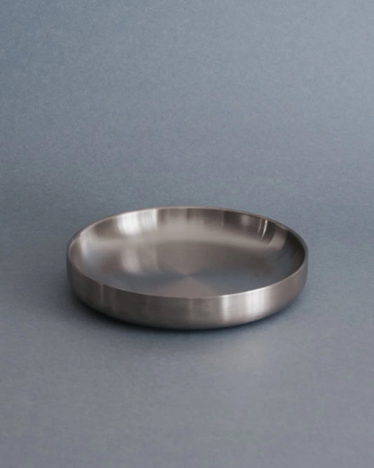 Silver round dinner plate on a gray background
