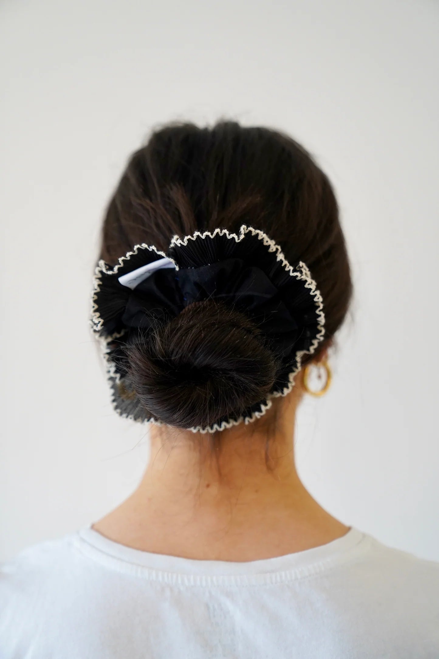 Person with a bun held in place by a decorative hair clip against a white background