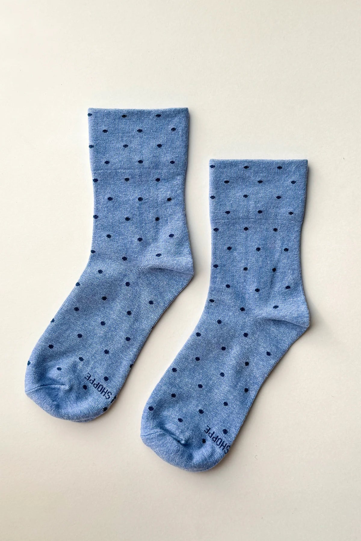 Pair of blue socks with black dots on a beige background