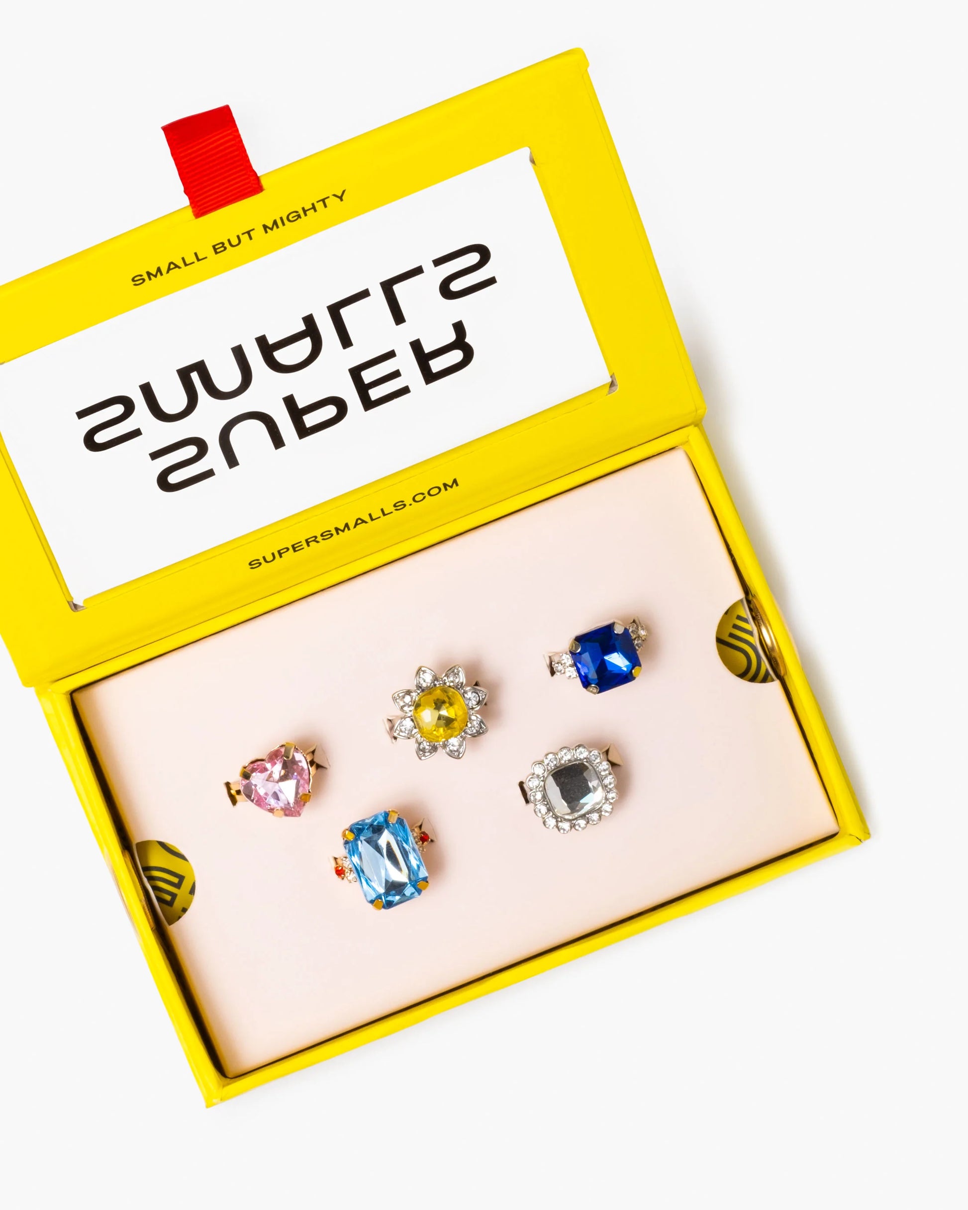 Set of colorful earrings in a 'Supermallz' branded box on a white background