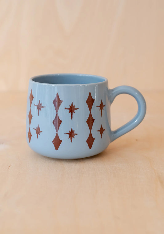 Light blue mug with red geometric pattern on a beige background