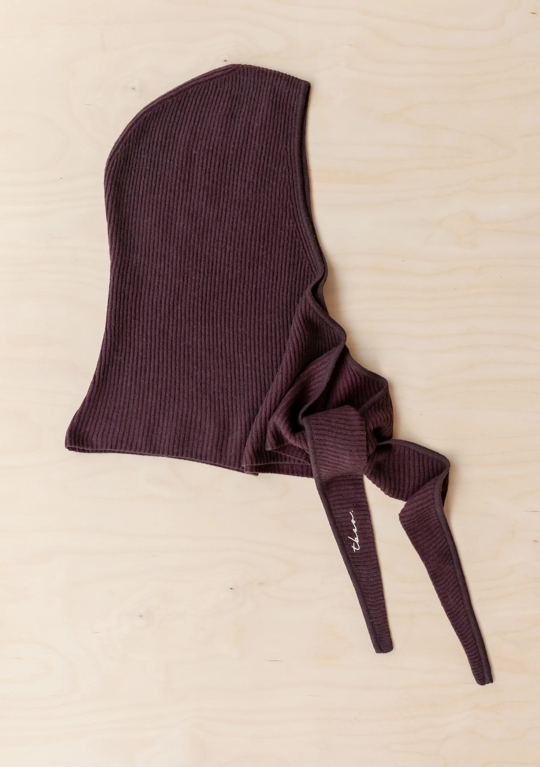 Brown ribbed baby bonnet on a beige background