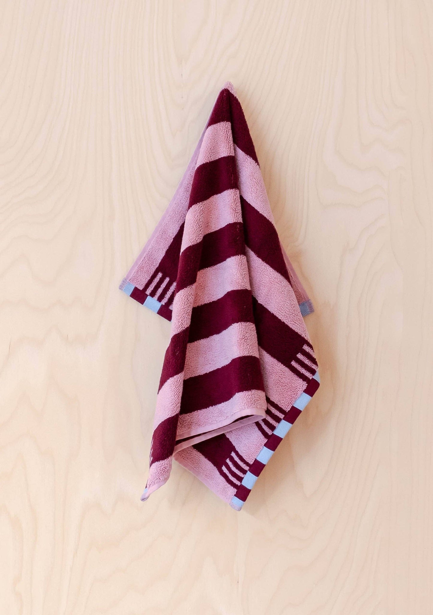 Striped towel with pink and purple pattern on a beige background