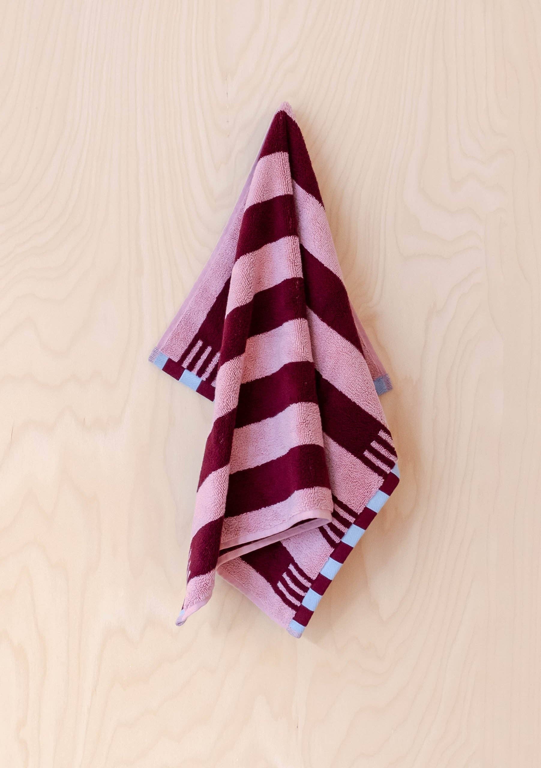 Striped towel with pink and purple pattern on a beige background