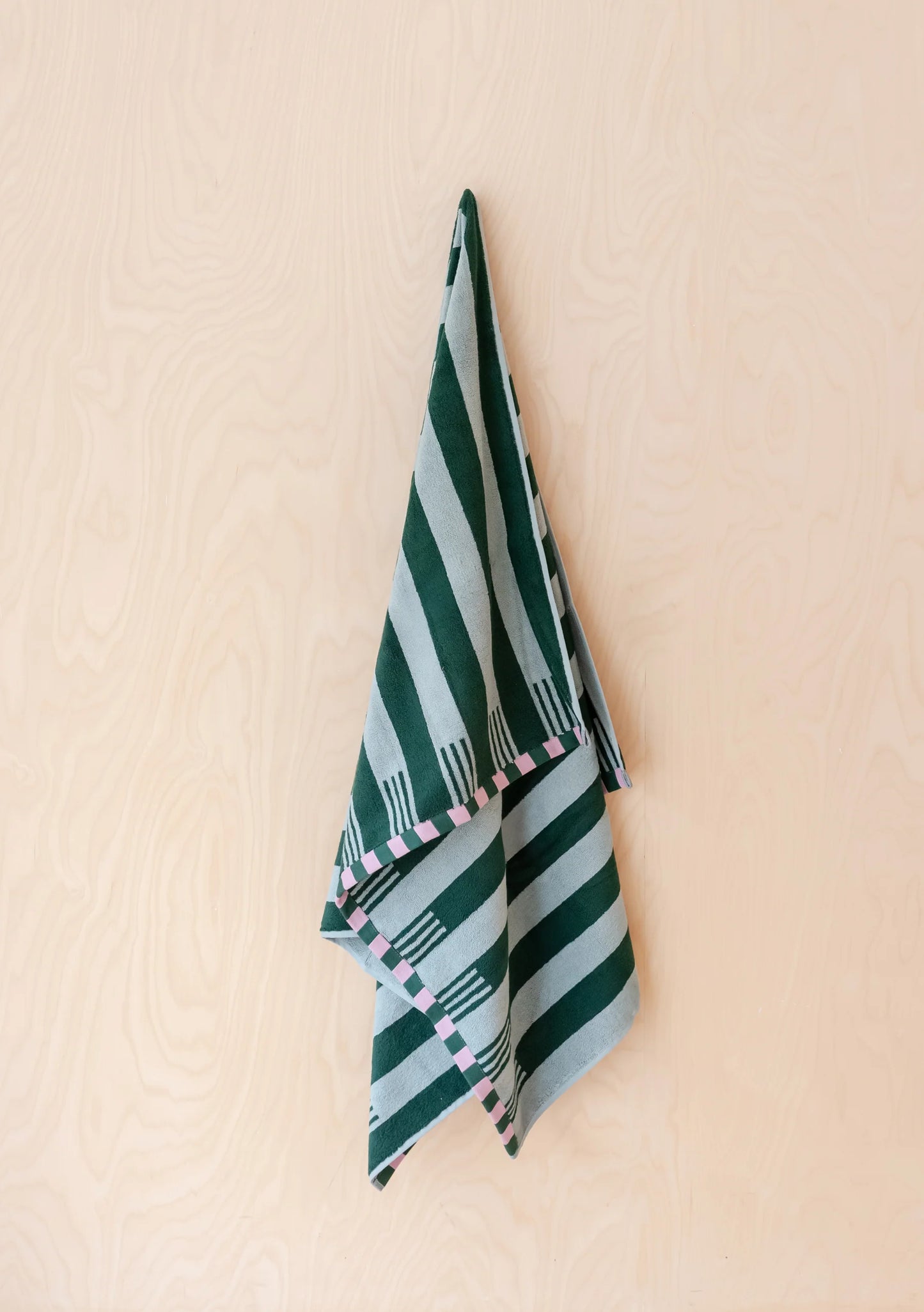 Green and blue striped towel hanging on a beige wall