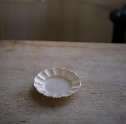 Small white ceramic plate on a wooden surface with a blurred background