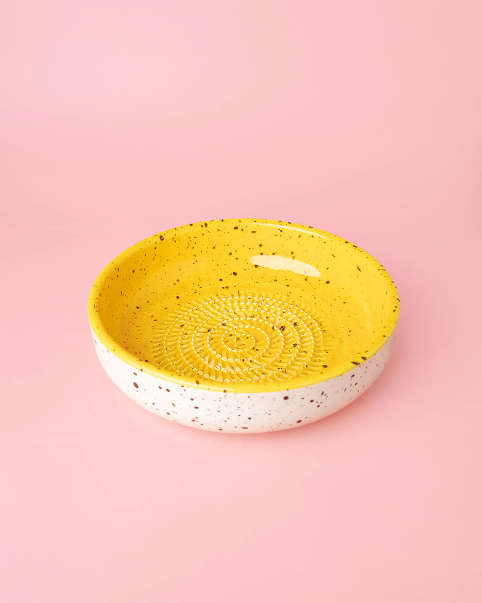 Tierra Cocida Medium Garlic Grater Plate in Yellow & White Canela colours on a pink background 
