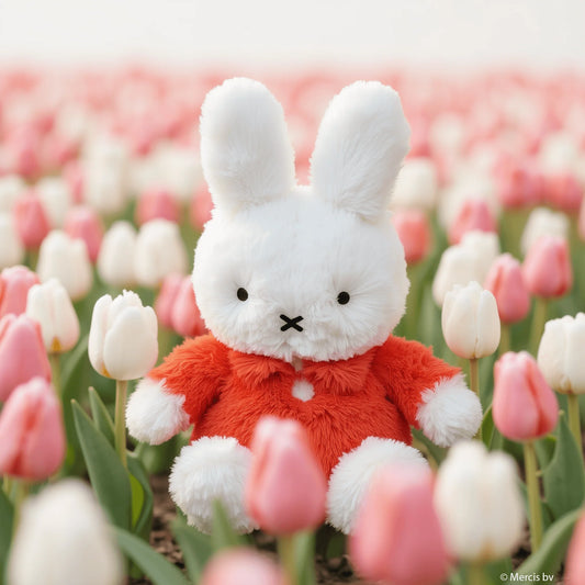 Plush toy rabbit in a red outfit surrounded by tulips