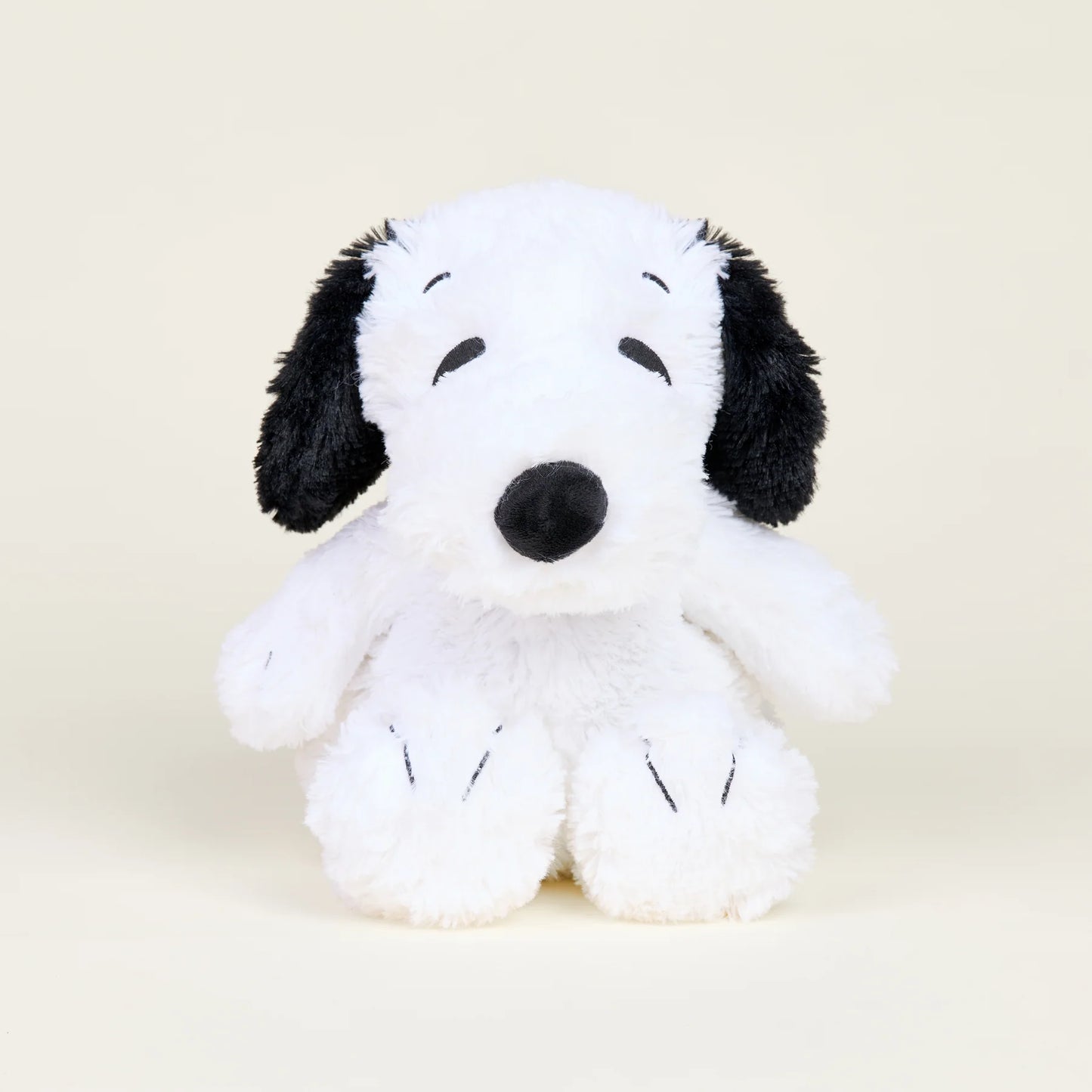 Plush toy resembling a black and white dog on a beige background