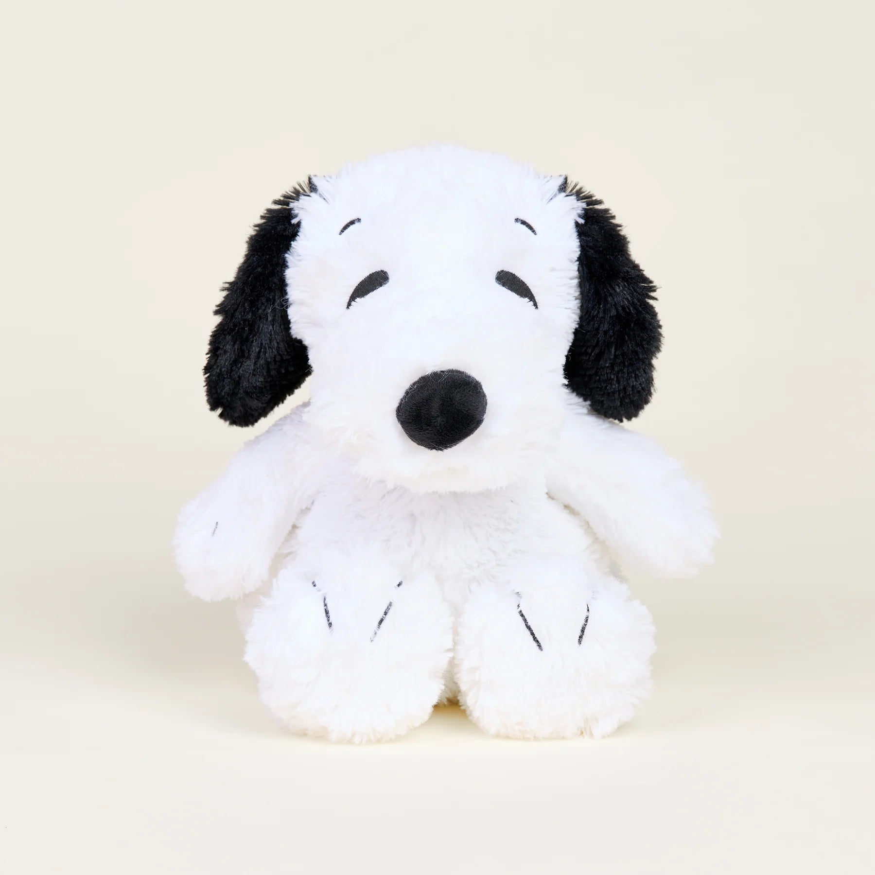 Plush toy resembling a black and white dog on a beige background
