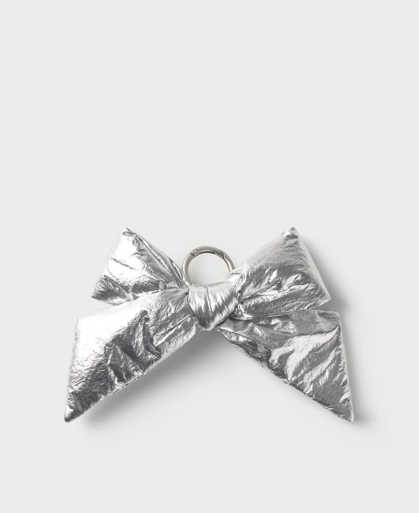 A metallic silver bow-shaped accessory with a crinkled foil texture and a small silver ring at the center, shown on a light gray background.
