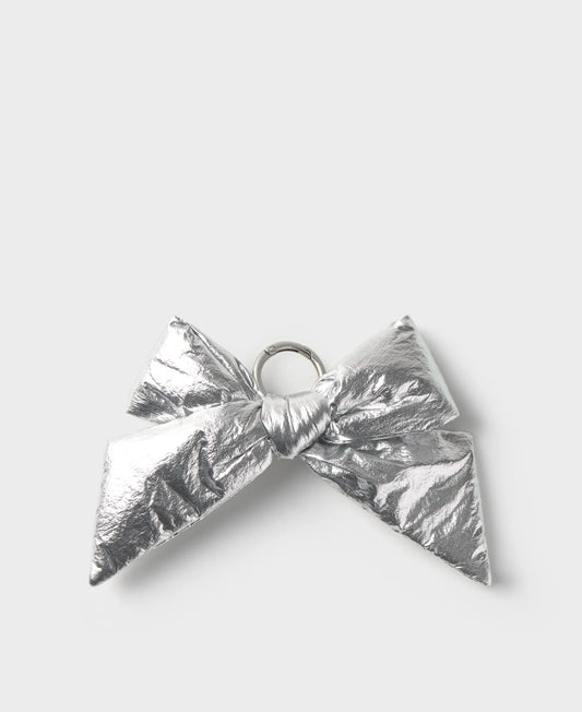 A metallic silver bow-shaped accessory with a crinkled foil texture and a small silver ring at the center, shown on a light gray background.