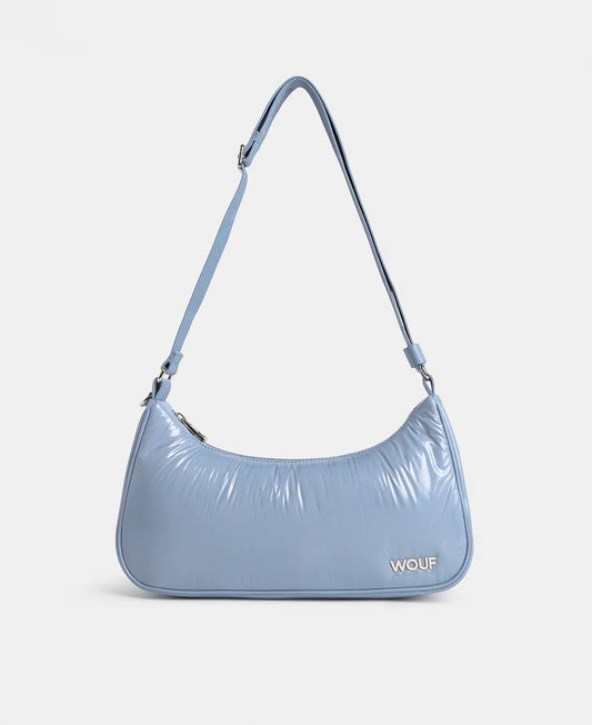 A light blue crescent-shaped shoulder bag with a glossy, crinkled texture and a matching adjustable shoulder strap, featuring the brand name 'WOUF' in gold lettering on the front, set against a plain light gray background.