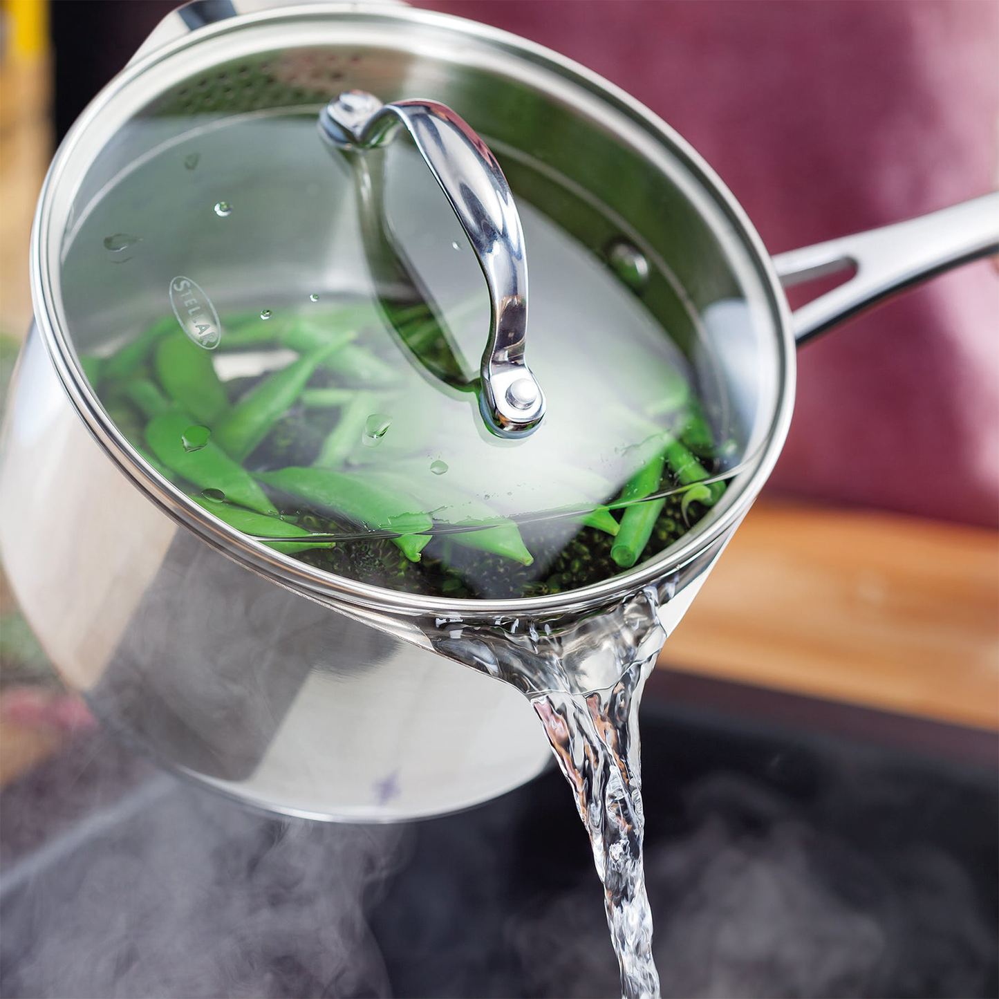 hot water being poured from the pot which is full of green vegetables 