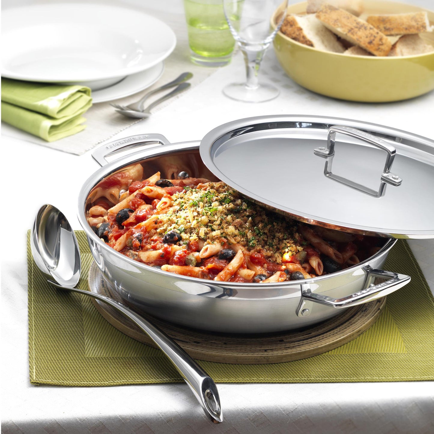 The casserole pan displayed on a dining table filled with a pasta dish