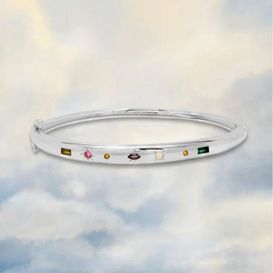silver bangle with gemstones on a cloudy sky background 
