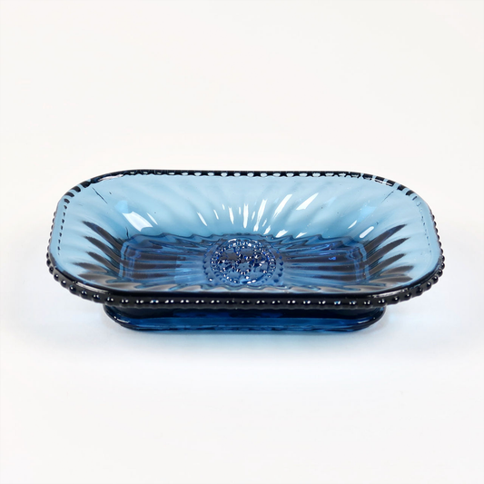 a blue glass soap dish with an embossed flower design in the centre