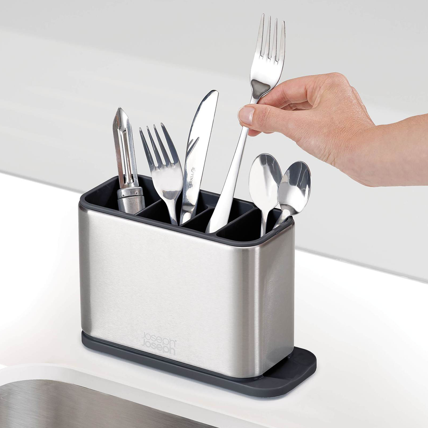 a person placing a fork into the cutlery drainer