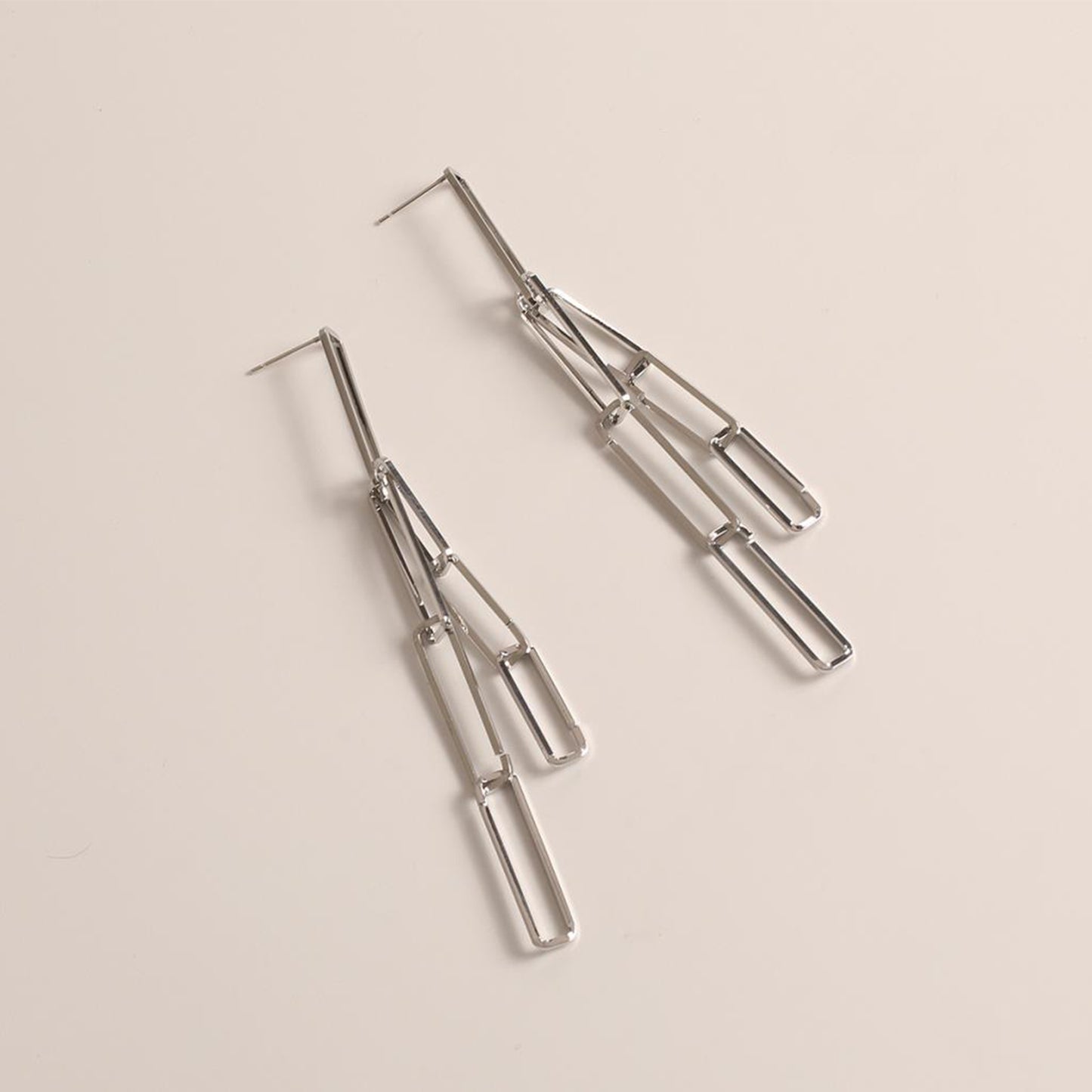 drop link earrings in silver on a pale pink background