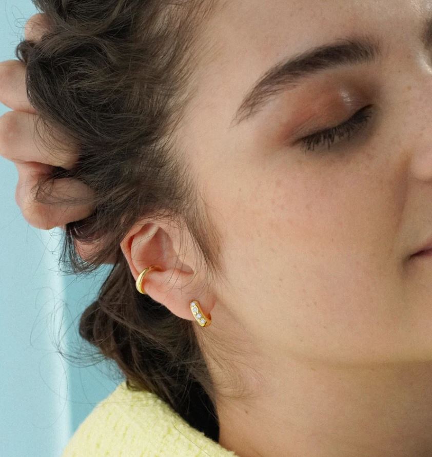 model wearing chunky huggie hoops in gold