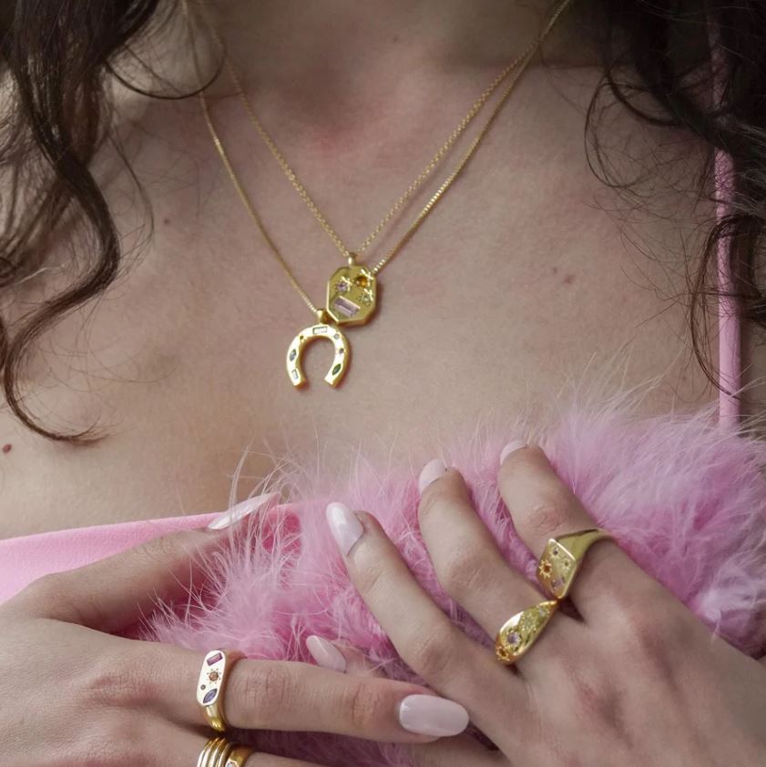 model wears the necklace styled with other gold jewellery 