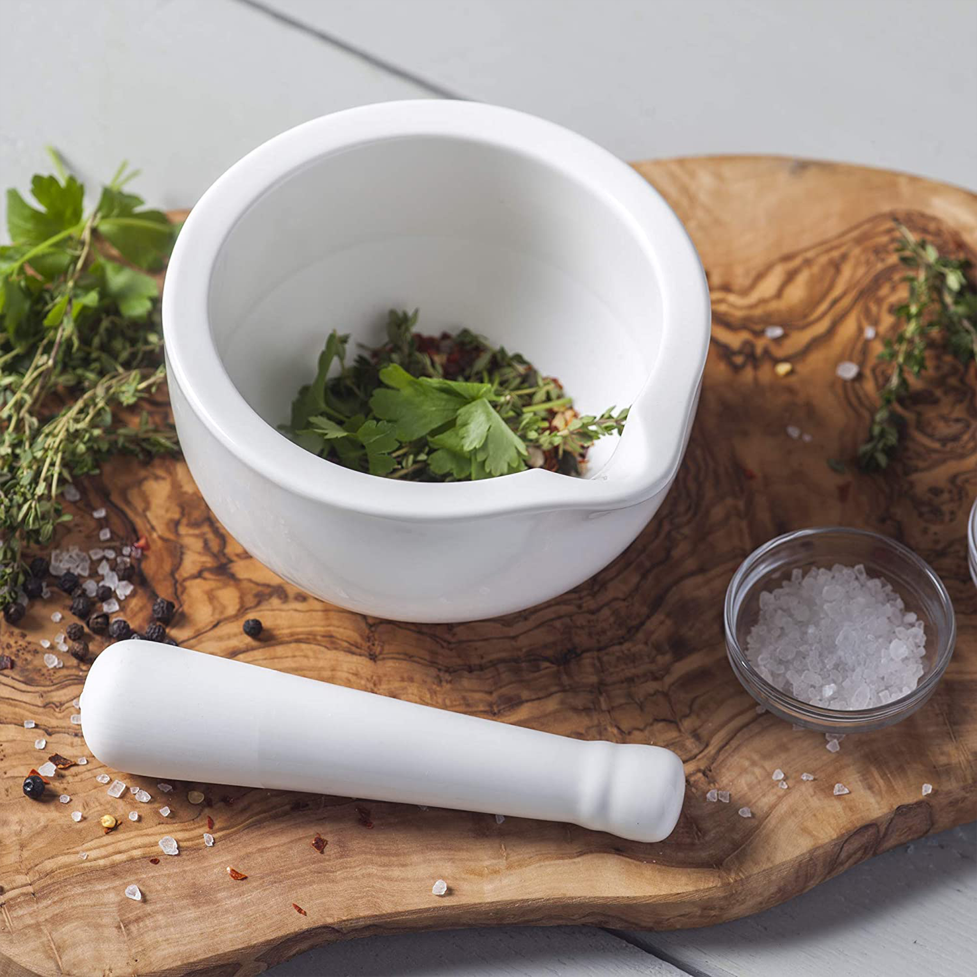 the mortar and pestle on a serving board filled with fresh herbs